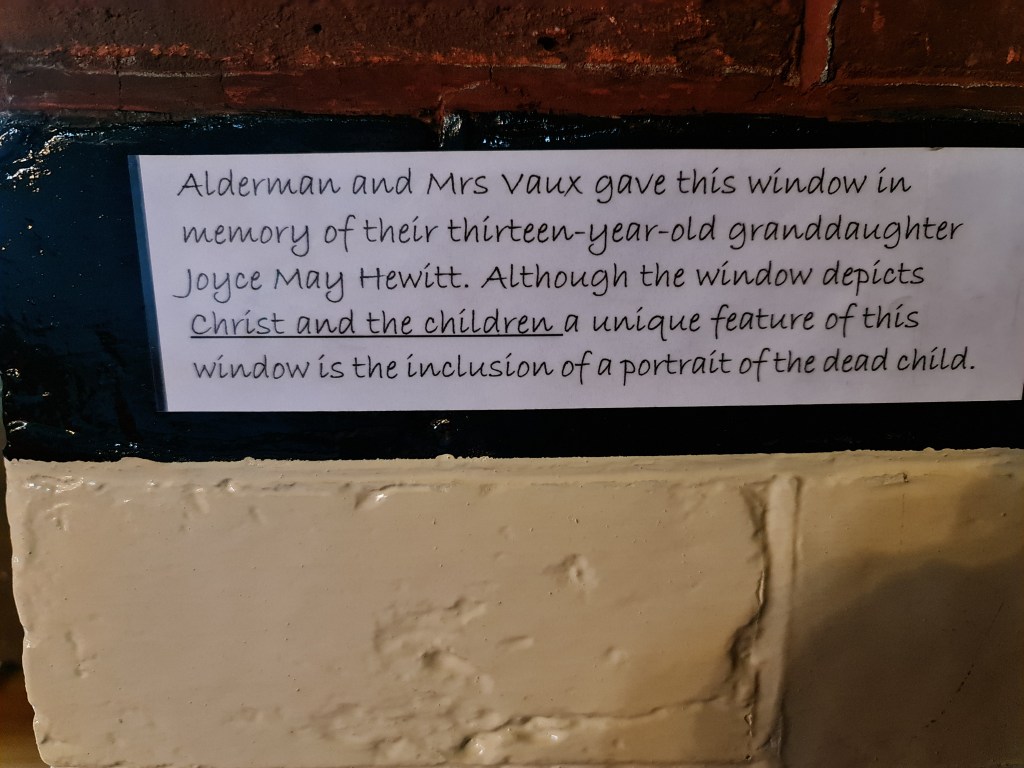 Alderman and Mrs Vaux gave this window in memory of their thirteen-year-old granddaughter Joyce May Hewitt.  Although the window depicts Christ and the Children a unique feature of this window is the inclusion of a portrait of the dead child."