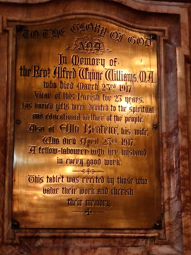 Brass plaque which reads: In memory of the Revd Alfred Wynne Williams MA who died March 23rd 1917. Vicar of this parish for 23 years.  His varied gifts were devoted to the spiritual and educational welfare of the people.  Also Ella Beatrice, his wife. Who died April 23rd 1917.  A fellow-labourer with her husband in every good work.  This tablet wa erected by those who value their work and cherish their memory."